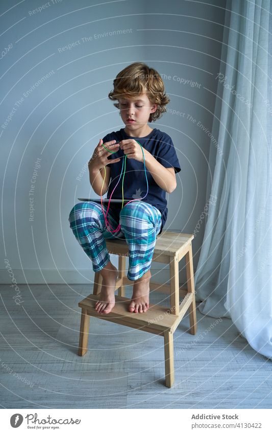 Kind mit Tablette lernt Katzenwiege-Spiel Schnur spielen lernen Wiege Kreativität Figur Hocker Pyjama heimwärts Junge Fokus Krawatte Vorstellungskraft Fähigkeit