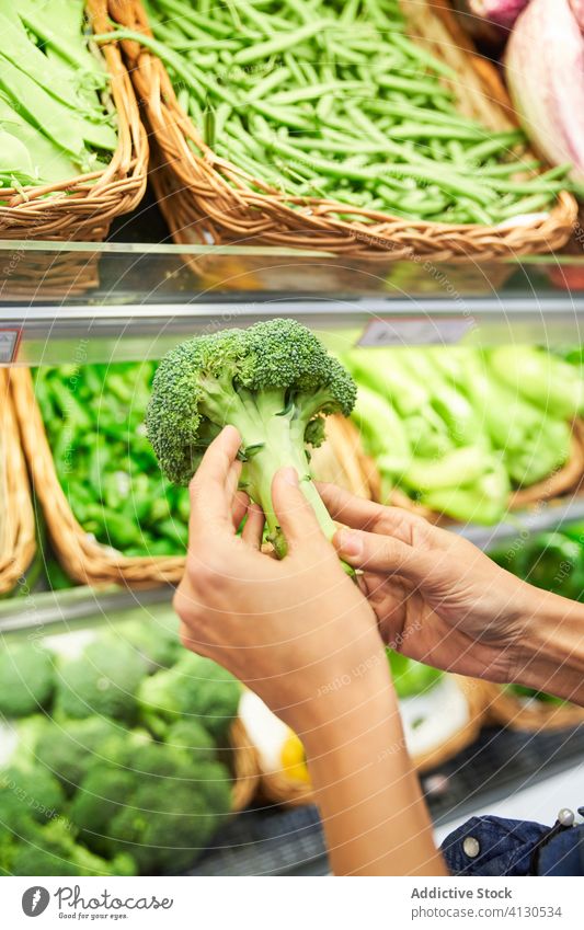 Weibliche Hand mit Brokkoli in der Hand in einem Obstladen Lebensmittel Gemüse Diät gesunde Ernährung fetter Mann beim Essen Top Fett Ergänzungsmittel grün roh