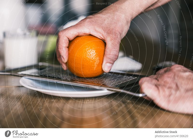 Hausfrau reibt Orangenschalen in der Küche orange Schale Gitter Bestandteil vorbereiten Koch Gebäck backen frisch aromatisch selbstgemacht Teigwaren Hand Rezept