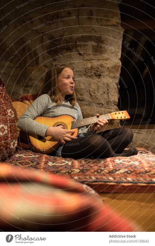 Ukulele spielendes Mädchen auf der Couch in einem Steinhaus während eines Urlaubs in Spanien Liege Haus Land üben Sofa Musik Komfort gemütlich Kantabrien