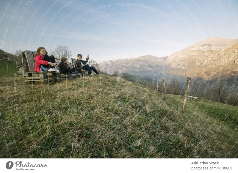 Gruppe von Kindern sitzt auf Holzbänken auf einem Hügel und genießt die Aussicht in Kantabrien Tourismus Zusammensein Ansicht Natur beobachten Spanien