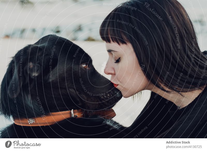 Junge Frau küsst schwarzen Hund Kuss Haustier Zusammensein Liebe Freund Begleiter bezaubernd Tier Eckzahn heimisch Reinrassig niedlich jung brünett Zuneigung