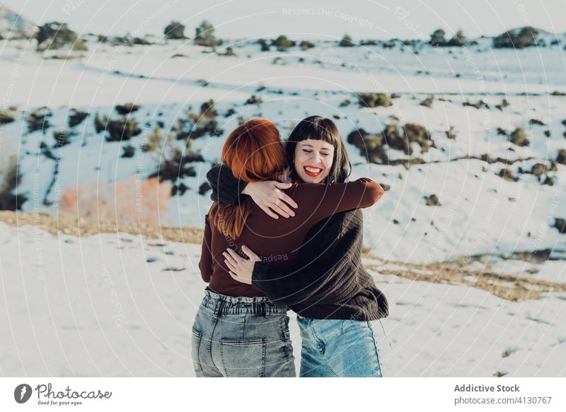Glückliche Frauen umarmen sich auf einem verschneiten Feld Umarmen Umarmung Freund heiter Zusammensein Schnee Winter Natur Landschaft lässig Freundin Lächeln
