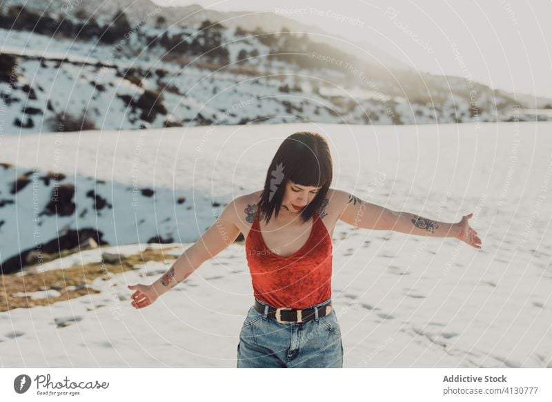 Unbekümmerte Frau auf verschneitem Feld im Sonnenschein sorgenfrei sich[Akk] entspannen Freiheit genießen Schnee Winter Natur trendy Spaß lässig Landschaft jung
