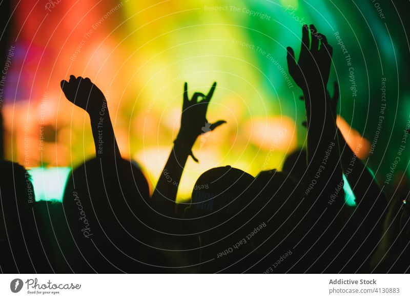 Menschen mit erhobenen Armen während der Show zeigen Konzert ausführen Menge Publikum Arme hochgezogen Silhouette Schauplatz leuchten neonfarbig Musik