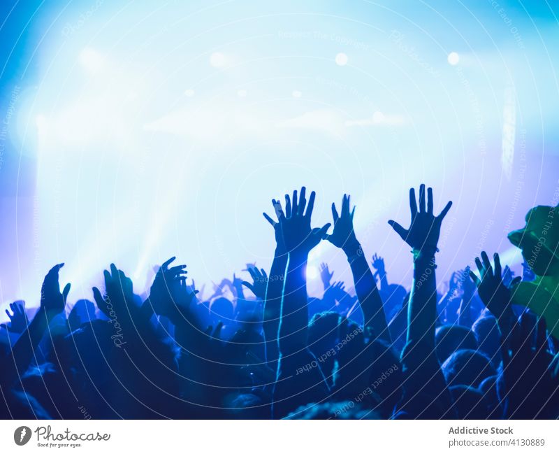 Menschen mit erhobenen Armen während der Show zeigen Konzert ausführen Menge Publikum Arme hochgezogen Silhouette Schauplatz leuchten blau neonfarbig Musik