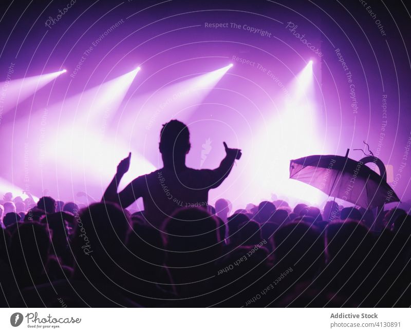 Menschen mit erhobenen Armen während der Show zeigen Konzert ausführen Menge Publikum Arme hochgezogen Silhouette Schauplatz leuchten purpur neonfarbig Musik