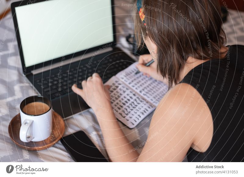 Frau macht sich Notizen in einem Notizbuch im Schlafzimmer zur Kenntnis nehmen Notebook Bett Laptop Kaffee schreiben Notizblock sich[Akk] entspannen Wochenende