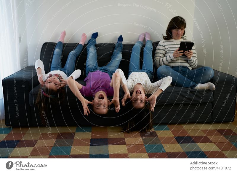 Eine Gruppe verspielter Kinder verbringt ihre Zeit zusammen auf dem Sofa, während die Mutter in der Nähe arbeitet Eltern Spaß unanständig