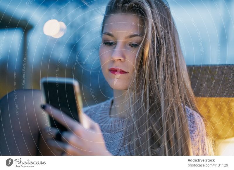 junges Mädchen, das nachts sein Handy benutzt Nacht Lehnen Bank durchsuchen E-Mail lesen Senden Wolkenkratzer prüfen nach unten Internet Nachricht vorbei Sitz