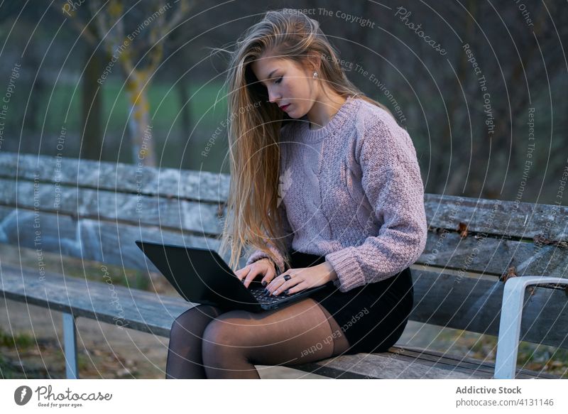 Seitenansicht einer lässigen Frau, die einen Laptop auf einer Holzbank im Park benutzt Bank Tippen E-Mail Internet benutzend Gerät Apparatur online