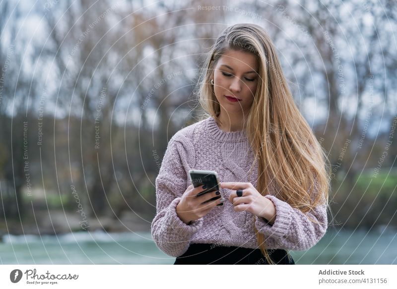 Junge Frau surft auf ihrem Smartphone, während sie sich im Park bei Sonnenuntergang ausruht Browsen ruhen Glück heiter froh benutzend zuschauend