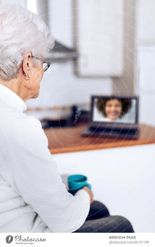 Ältere Frau trinkt Tee und spricht mit ihrer Tochter am Laptop Senior Videoanruf heimwärts Coronavirus benutzend online trinken Tasse Küche Mutter reden Becher