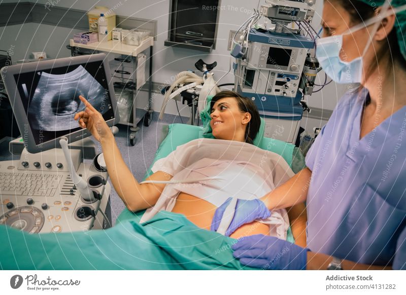 Gynäkologe untersucht Patientin während der Ultraschalluntersuchung in der Klinik Frauenarzt Ultraschall-Scan geduldig schwanger Monitor Embryo Mundschutz