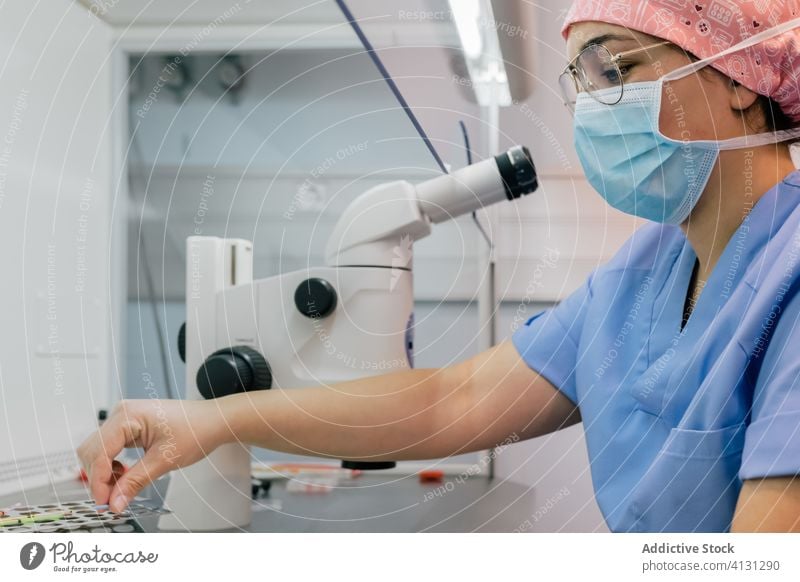Arzt, der Zellen unter dem Mikroskop untersucht Frau Labor Tisch Arbeit Klinik Uniform Medizin untersuchen Krankenhaus professionell Fruchtbarkeit Spezialist