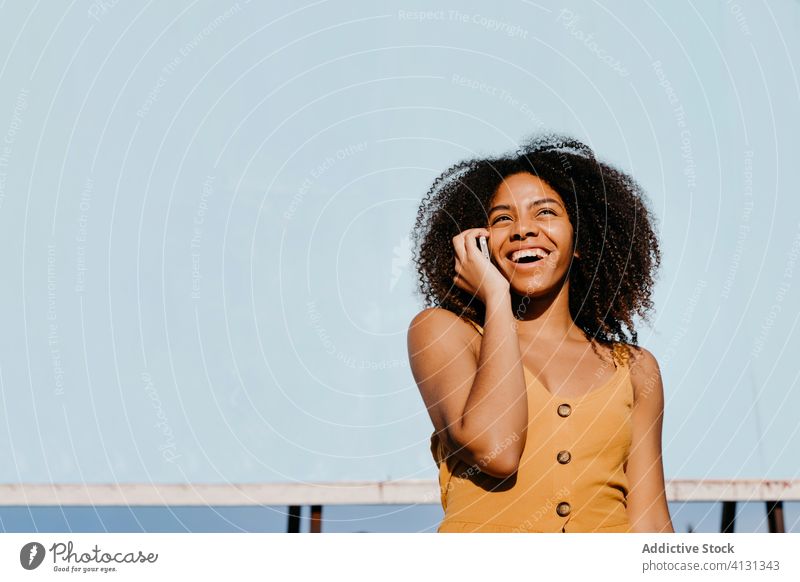 Junge zufriedene ethnische Frau benutzt Handy auf der Straße gegen leere große Tafel in einem Vorort Smartphone Plakatwand verwenden Freude Transparente