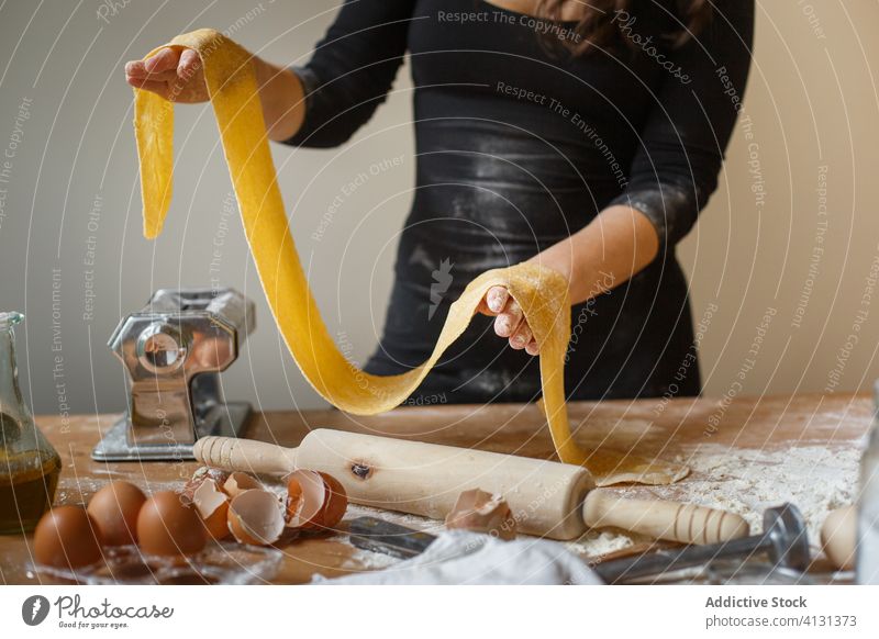 Gesichtslose Frau mit gerolltem Teig in der Küche Teigwaren elastisch Spätzle selbstgemacht Koch Mehl roh Küchengeräte rollen Speise Ei vorbereiten Bestandteil