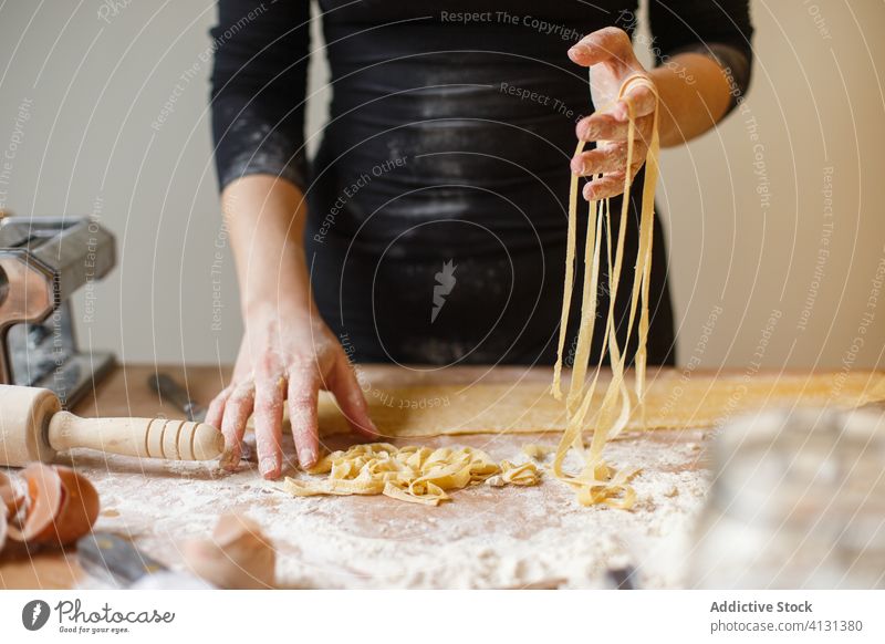 Nicht erkennbare Frau mit geschnittener roher Pasta Spätzle selbstgemacht Teigwaren Gurt dünn Streifen Gebäck Koch Tisch Mehl Küchengeräte rollen Eierschale