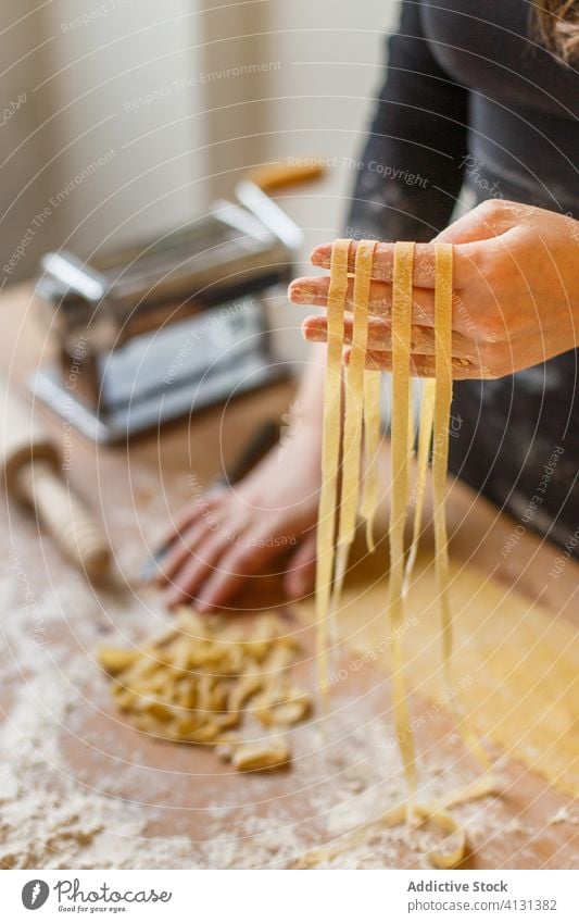 Nicht erkennbare Frau mit geschnittener roher Pasta Spätzle selbstgemacht Teigwaren Gurt dünn Streifen Gebäck Koch Tisch Mehl Küchengeräte rollen Eierschale