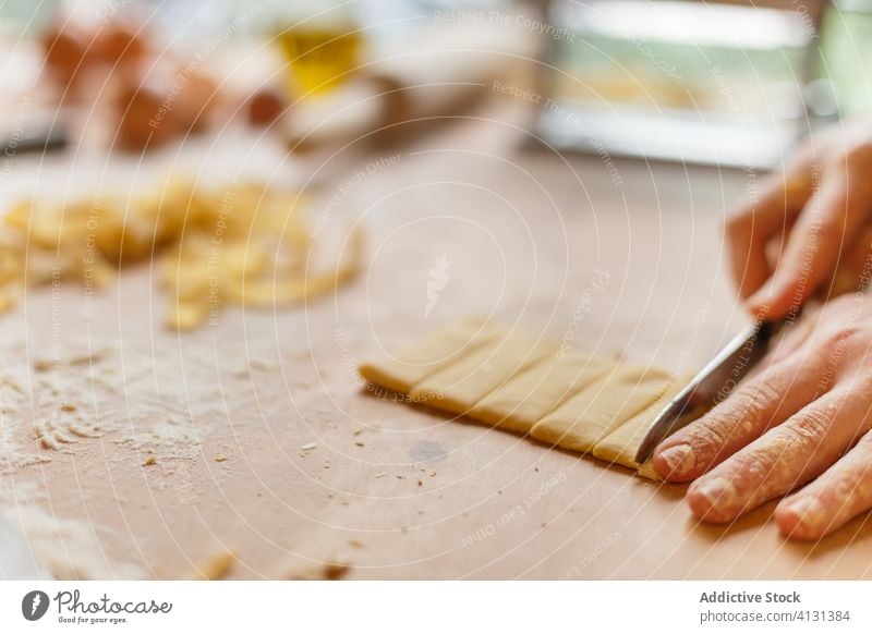 Unbekannte Person schneidet Nudelteig auf dem Tisch Teigwaren Spätzle selbstgemacht geschnitten Streifen Koch dünn Messer Mehl vorbereiten Küche rollen Prozess