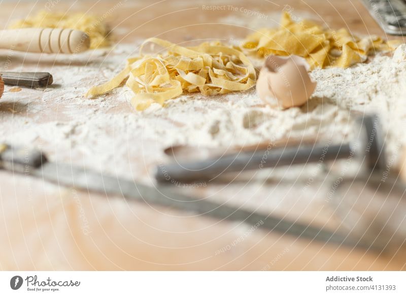 Unordentlicher Tisch mit Nudelzutaten und Kochzubehör auf Mehl Spätzle roh selbstgemacht Bestandteil unordentlich Eierschale Küchengeräte Utensil Kochen