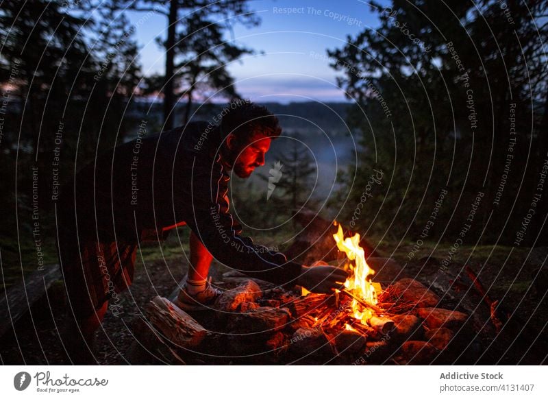 Mann mit Brennholz beim Lagerfeuermachen im Wald Wohnmobil Freudenfeuer Nacht Totholz Aufwärmen männlich Windstille Reisender ruhig Wälder Abenddämmerung