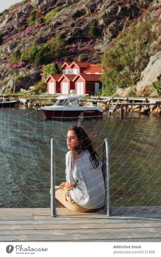 Reisende Frau sitzt auf einem Holzsteg und bewundert die Meereslandschaft Tourist Promenade sich[Akk] entspannen bewundern Boot Windstille Ausflug ruhen