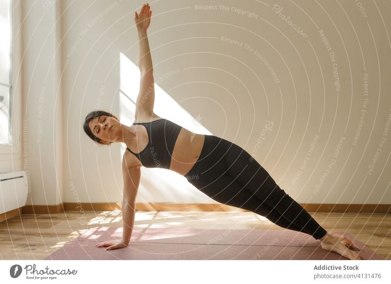 Frau übt seitliche Planke auf Matte zu Hause Yoga Seitenbrett Gleichgewicht Asana Gesundheit heimwärts Sport üben Augen geschlossen Unterlage vasishtasana