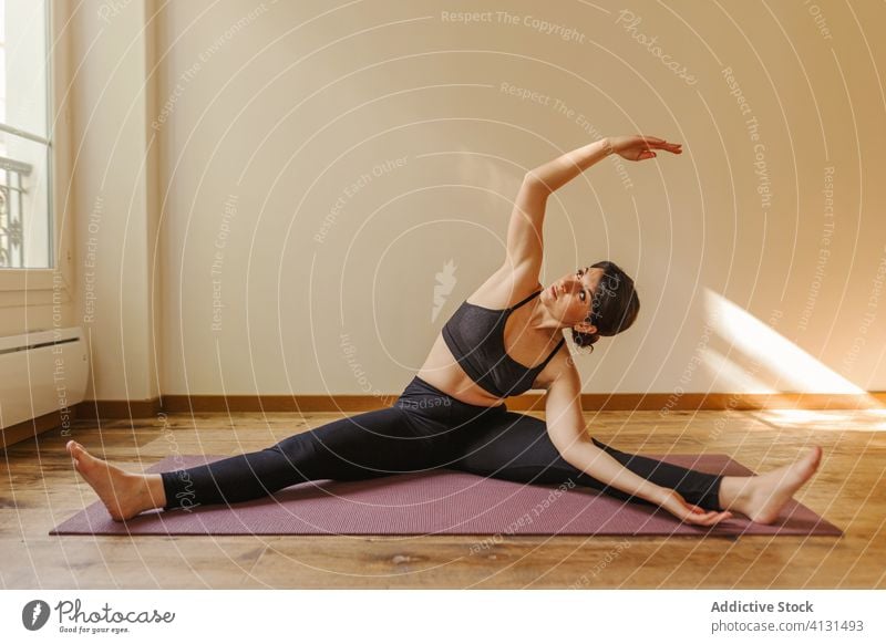 Flexible Frau in Bootspose sitzend beim Yoga-Workout üben Boot-Pose Dehnung Vitalität Füße berühren beweglich Gesunder Lebensstil Training Unterlage fokussiert