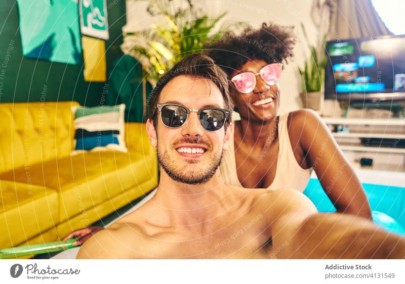Lächelndes Paar macht Selfie während einer Party zu Hause aufblasbar Pool zu Hause bleiben Selbstisolierung genießen soziale Distanzierung fotografieren