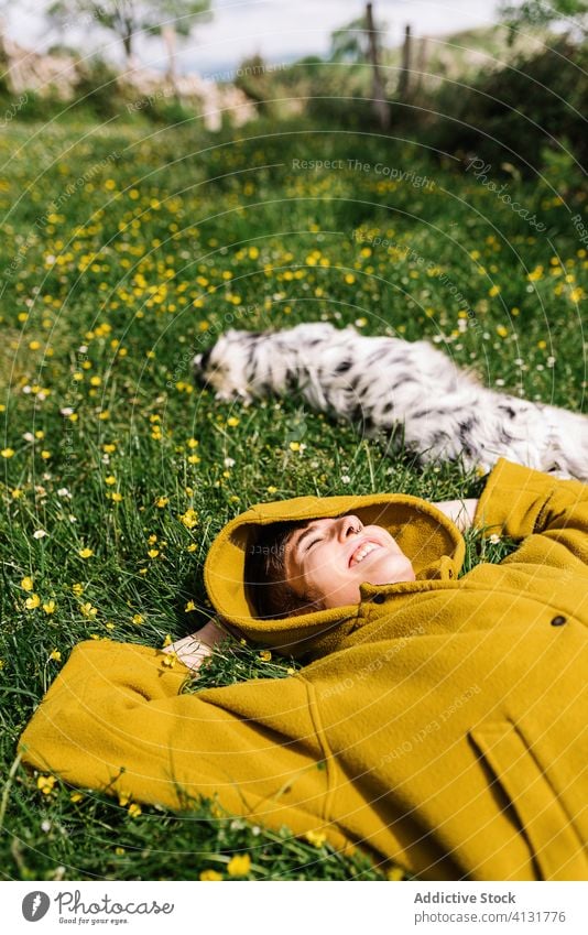 Fröhliche Frau mit Hund auf der Wiese genießen Sonne Zusammensein Lügen heiter Blume Inhalt Asturien Spanien Eckzahn Natur Glück Tier Haustier Sommer heimisch