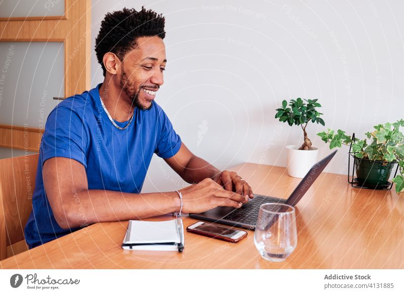 Ethnischer Mann tippt zu Hause während der Selbstisolierung am Laptop heimwärts Tippen abgelegen Arbeit heiter freiberuflich Bund 19 Coronavirus benutzend