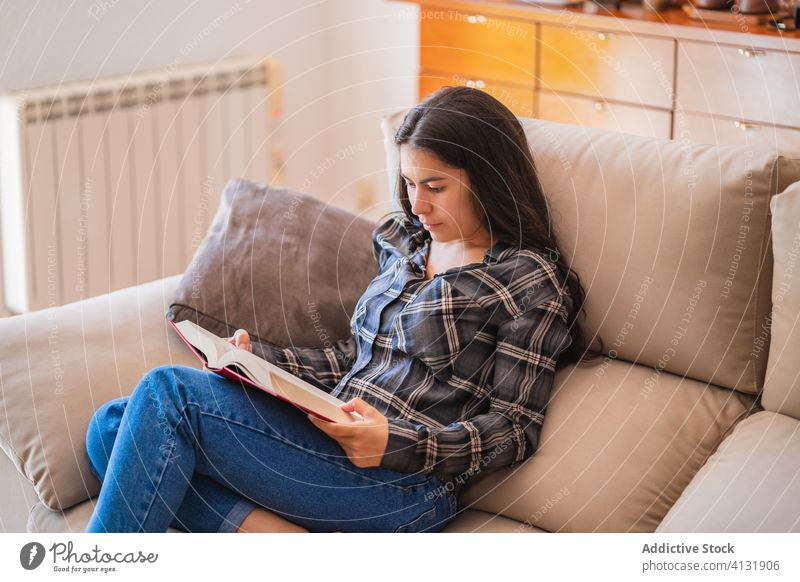 Junge Frau liest zu Hause ein Buch lesen heimwärts Sofa lässig ruhen genießen jung Freizeit Lifestyle Komfort Liege gemütlich sitzen Hobby Literatur Kälte