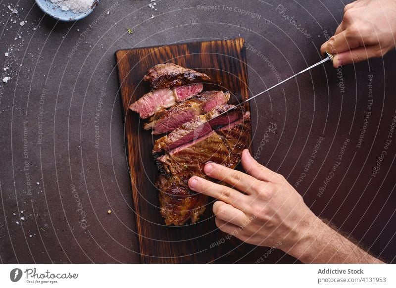 Hände beim Schneiden von Rindersteak ribeye Steak gegrillt schwarz angus Grillrost Lebensmittel Fleisch Küche Beefsteak gebraten geschmackvoll aufgeschnitten