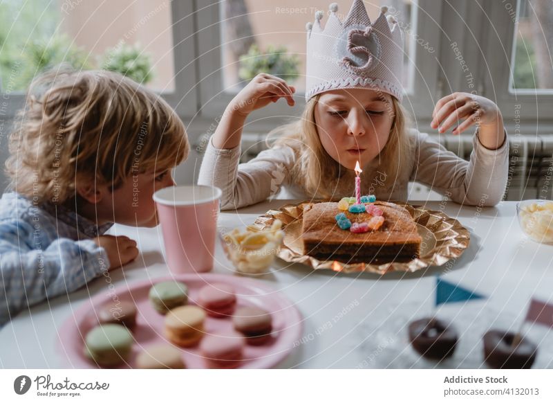 Kleines Mädchen bläst Kerze auf Geburtstagskuchen während einer Party zu Hause Kuchen Wunsch Schlag Glück feiern heimwärts Freude charmant Krone Filz dekorativ