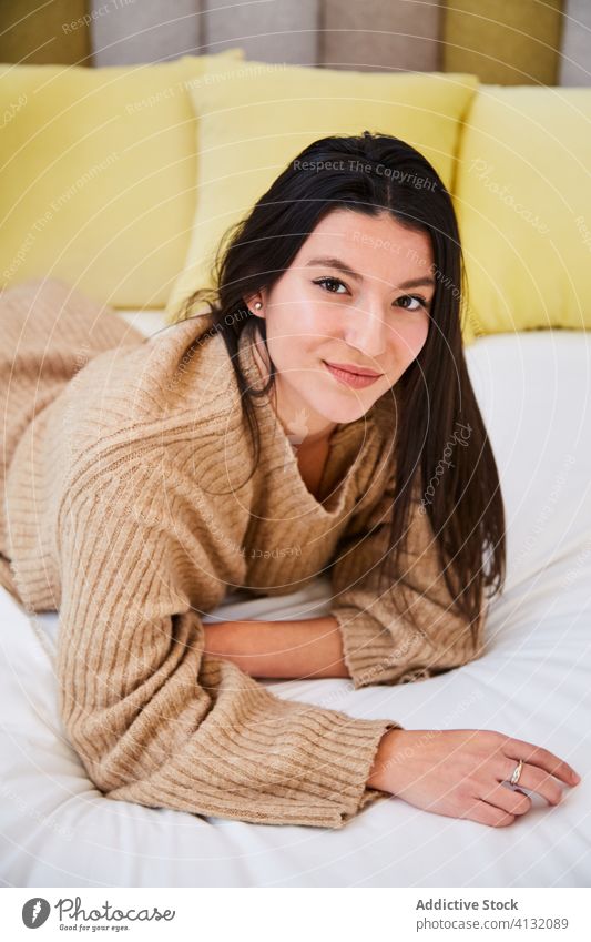 Unbeschwerte Frau chillt auf dem Bett zu Hause weich charmant Kälte sich[Akk] entspannen Schlafzimmer Komfort gemütlich Lügen Übergröße Pullover modern ruhen