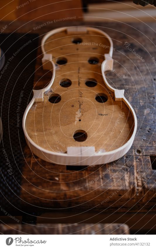 Resonanzboden einer handgefertigten Geige auf schäbiger Holzoberfläche im Arbeitsraum Prozess Werkstatt Golfloch Handwerk Instrument hölzern Verarbeitung