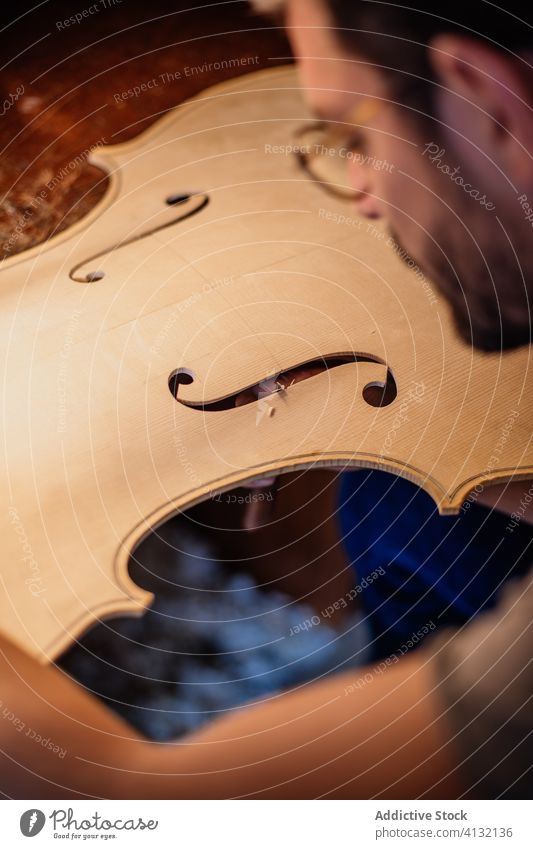 Mann beendet das Schneiden von F-Löchern in den Resonanzboden, während er in der Werkstatt eine Geige herstellt Kunstgewerbler geschnitten f-Loch Werkzeug