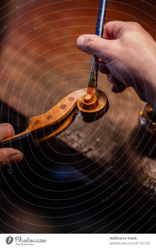 Kunsthandwerker beim Lackieren einer Geigenschnecke mit dem Pinsel in der Werkstatt Firnis blättern Farbe Bürste Hand Werkzeug Kunstgewerbler Handwerk Person