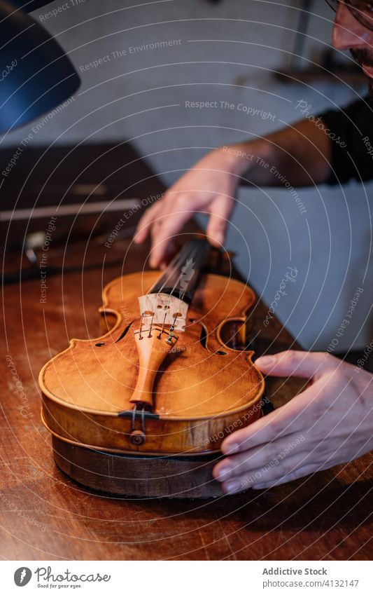 Handwerker beim Einstellen der Saiten einer handgefertigten Geige in der Werkstatt Mann Schnur Kunstgewerbler ausrichten einstellen Klang Kunsthandwerker Person