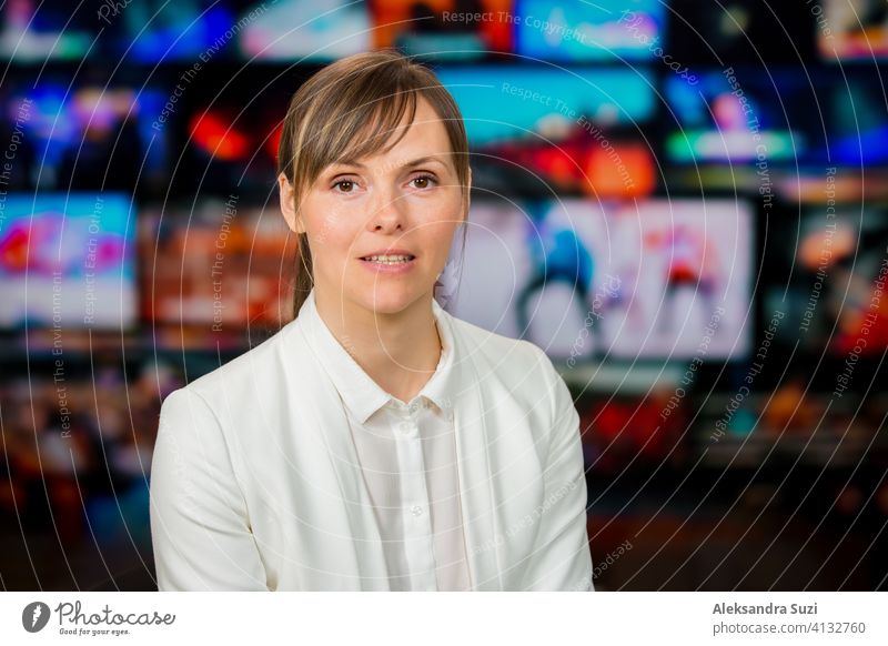 Eine Moderatorin, die live über aktuelle Nachrichten berichtet, sitzt im Fernsehstudio. Hintergrund von mehreren Bildschirmen von Broadcast-Kontrollraum. Journalismus Konzept