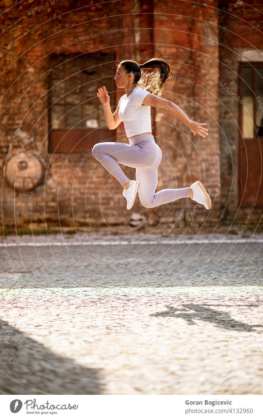 Junge Frau juping hoch während des Trainings in der städtischen Umgebung Großstadt jung passen Fitness springen Athlet urban Sport sportlich Aktivität Kaukasier