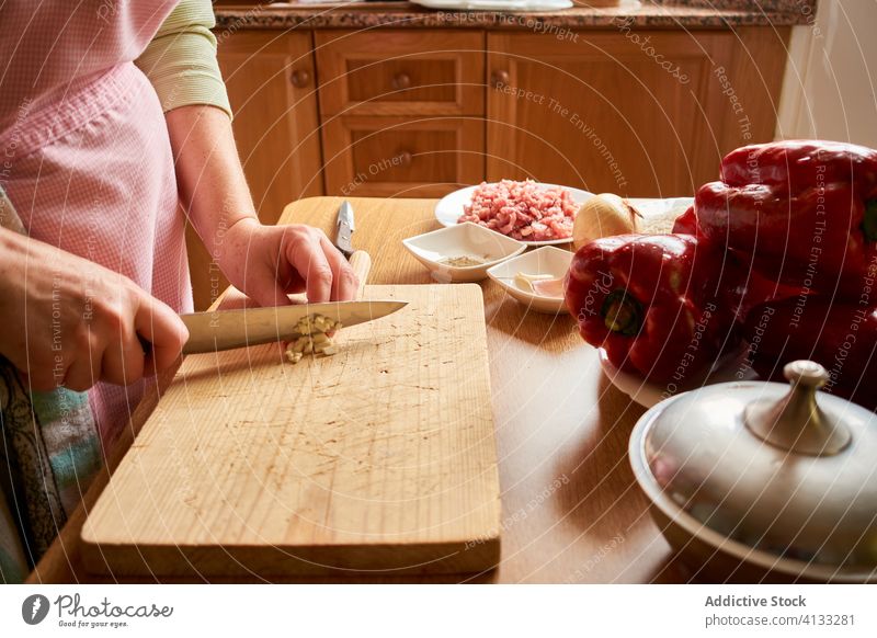 Anonyme Frau beim Kochen in der Küche Bestandteil vorbereiten Prozess geschnitten Knoblauch gefüllte Paprikaschoten Lebensmittel kulinarisch Tisch frisch