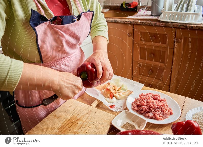 Anonyme Hausfrau bereitet Pfeffer zum Kochen vor gefüllte Paprikaschoten Frau Küche älter Lebensmittel vorbereiten Prozess geschnitten Bestandteil frisch Gemüse
