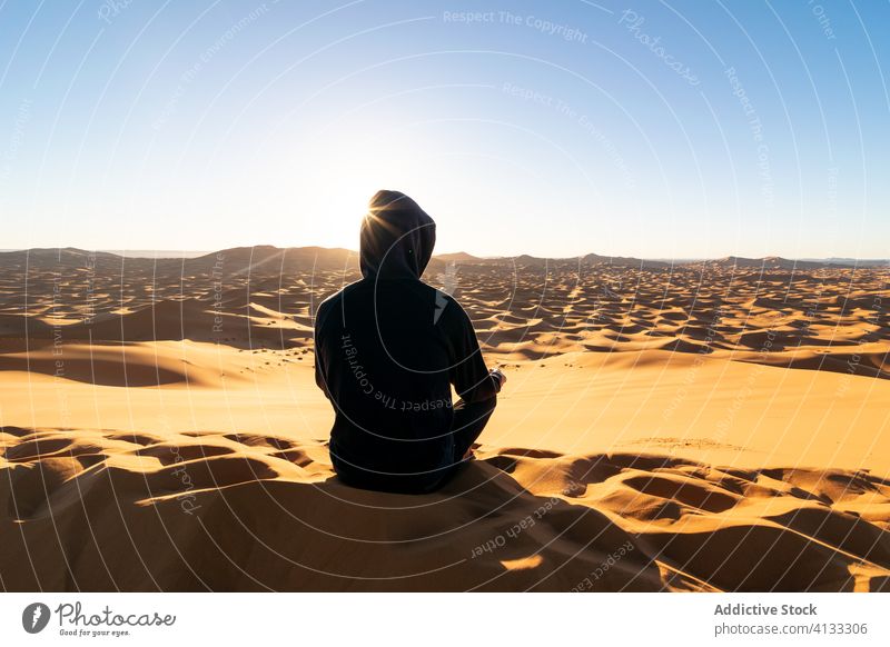 Unerkennbarer Reisender, der sich bei Sonnenuntergang in der Wüste im Sand entspannt wüst Düne bewundern Tourist majestätisch Landschaft Marokko Afrika