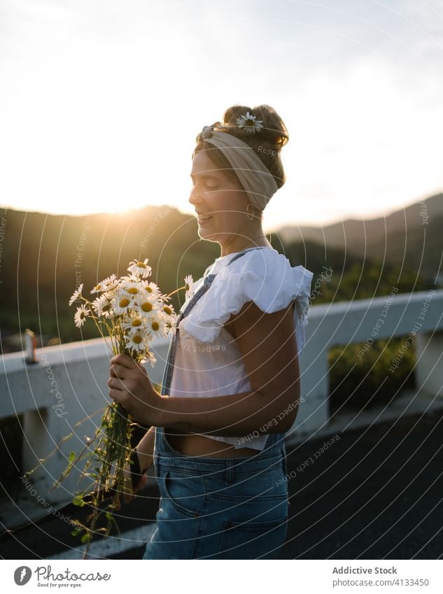 Glückliche junge Dame mit einem Strauß frischer Kamille auf dem Balkon Frau Blumenstrauß Sonnenuntergang Sommer Windstille Terrasse sorgenfrei sonnig Blütezeit