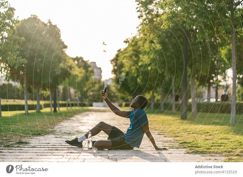Schwarzer Mann macht Selfie Telefon Glück Park männlich entspannt aussruhen im Freien Mobile Lächeln schwarz Afrikanisch Menschen jung Fröhlichkeit heiter