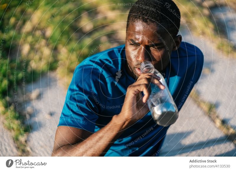 Sportlicher schwarzer Mann trinkt Wasser Afrikanisch trinken Fitness hinsetzend stark Biegung Körper passen Muskel Bizeps Waffen Athlet Stärke Lifestyle