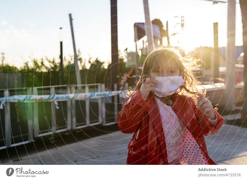 Ethnisches Mädchen mit chirurgischer Maske auf der Straße" medizinisch Mundschutz Kind genießen Wochenende Bund 19 behüten ethnisch Kindheit heiter Glück