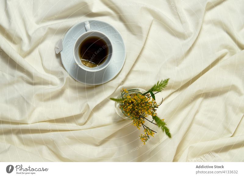 Keramischer weißer Becher mit Tee auf dem Bett Frühstück aromatisch grün Getränk trinken lecker Erfrischung Tasse geschmackvoll Blumenstrauß heiß heimwärts
